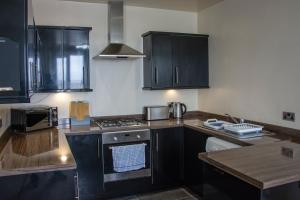 a kitchen with black cabinets and a stove top oven at Morecambe Central balcony with sea view in Morecambe