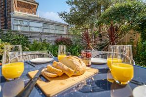 a table with a tray of bread and glasses of orange juice at Large family house in Worthing - 5 mins from beach in Worthing
