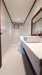 ein weißes Badezimmer mit einem Waschbecken und einem Spiegel in der Unterkunft Nongsa Village in Nongsa