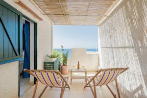 Habitación con 2 sillas y balcón con mesa. en Isulidda Gaia Mare en San Vito lo Capo