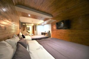 1 dormitorio con 2 camas y TV en la pared en The Gentle Hotel en Busan
