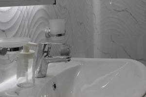 - un lavabo blanc avec un robinet et un miroir dans l'établissement شقق كيان الحجاز, à Djeddah