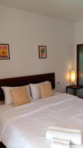 een slaapkamer met een groot wit bed met 2 kussens bij The My Home Resort in Prachuap Khiri Khan