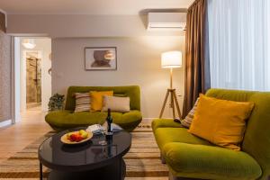 a living room with two green chairs and a table at Rox Central Apartments 4 in Timişoara