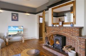 uma sala de estar com uma lareira de tijolos e uma televisão em Large family house in Worthing - 5 mins from beach em Worthing