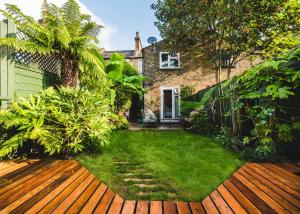einen Garten mit einer Holzterrasse vor einem Haus in der Unterkunft Stunning 2BR, split-level Flat w garden, Deptford in London