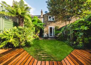 a garden with a wooden deck in front of a house at Stunning 2BR, split-level Flat w garden, Deptford in London