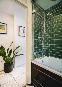W łazience znajduje się wyłożona zielonymi kafelkami prysznic i wanna. w obiekcie Stunning 2BR, split-level Flat w garden, Deptford w Londynie