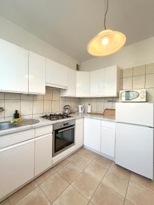 グディニャにある19 Gdynia Centrum - Apartament Mieszkanie dla 8 osの白いキャビネットと照明付きのキッチンが備わります。