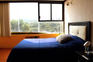 - une chambre avec un lit bleu et une grande fenêtre dans l'établissement ArcoSuite, Espacio Ideal para Reuniones Y Hospedaje, à Mexico