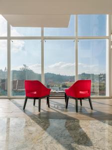 two red chairs in a room with a large window at Mango Hill Central Ooty in Ooty