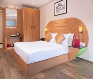 a bedroom with a large bed with a wooden headboard at Mango Hill Central Ooty in Ooty