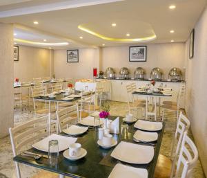 a dining room with tables and chairs and a kitchen at Mango Hill Central Ooty in Ooty