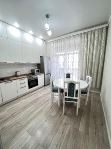 cocina con mesa blanca y sillas en una habitación en Прекрасное местечко Barys City, en Taldykolʼ