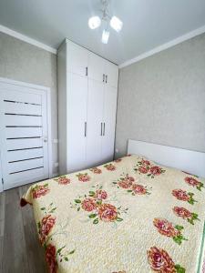1 dormitorio con 1 cama con colcha de flores en Прекрасное местечко Barys City, en Taldykolʼ