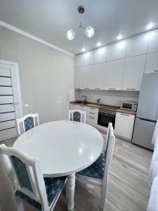 cocina blanca con mesa blanca y sillas en Прекрасное местечко Barys City, en Taldykolʼ