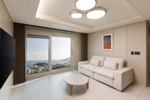 a living room with a couch and a table and a window at NewCZ Osiria Residence in Busan