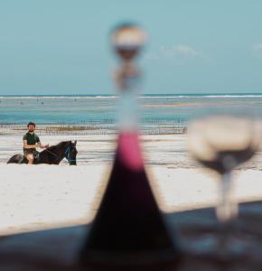 a person riding a horse on the beach at BIANCO AZZURRO Hotel & Restaurant in Pwani Mchangani