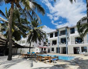 a resort with a swimming pool and palm trees at BIANCO AZZURRO Hotel & Restaurant in Pwani Mchangani