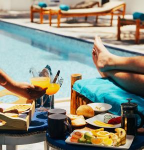 una mesa con una bandeja de comida junto a una piscina en BIANCO AZZURRO Hotel & Restaurant, en Pwani Mchangani