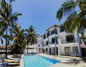 a resort with a swimming pool and palm trees at BIANCO AZZURRO Hotel & Restaurant in Pwani Mchangani