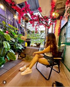 a girl sitting in a chair in a flower shop at Old House Homestay in Hanoi