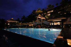 a person swimming in a swimming pool at night at Taj Wayanad Resort & Spa, Kerala in Wayanad