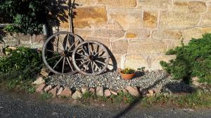 uma roda de carroça de madeira ao lado de uma parede de pedra em Ferienwohnung DaWi Röhrenfurth em Melsungen