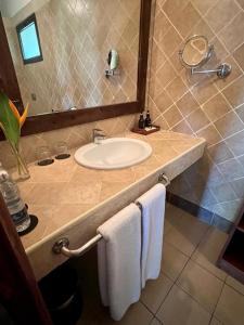 W łazience znajduje się umywalka, lustro i ręczniki. w obiekcie Hotel Club Dongwe w mieście Pingwe