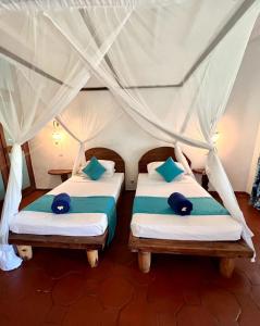 - 2 lits dans une chambre à baldaquin dans l'établissement Hotel Club Dongwe, à Pingwe