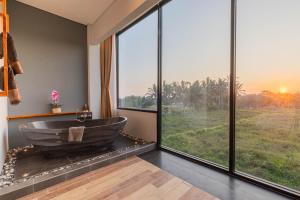 a bathroom with a large tub with a large window at Green Sala Villa in Ubud