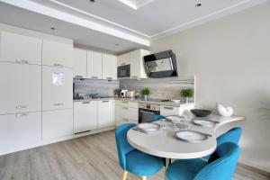 cocina con mesa blanca y sillas azules en Val Détente - Appartement à proximité immédiate de la plage, en Pléneuf-Val-André