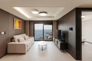 a living room with a couch and a tv at NewCZ Osiria Residence in Busan