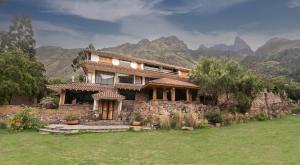 una casa de piedra con montañas en el fondo en CASA RAIZ Handmade House Luxury Stay, en Calca