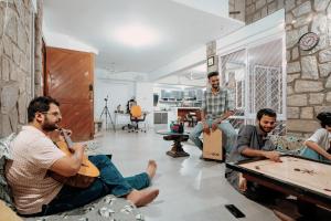 a group of men sitting in a living room playing music at BYOC Hostels in Bangalore
