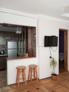 a kitchen with two stools and a tv on a wall at Jacquard Apartment in the centre of Kutaisi in Kutaisi +11 photos