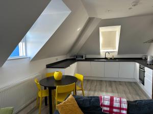 a kitchen with a table and yellow chairs in a room at Lovely 2-bedroom apartment in the heart of chelmsford in Chelmsford