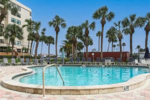 a pool with chairs and palm trees in a resort at Harbor Towers 1 Bedroom Pool View in Siesta Key