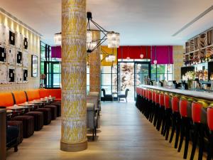 a restaurant with orange chairs and a bar at Ham Yard Hotel, Firmdale Hotels in London