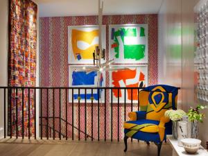 a living room with a chair and colorful wallpaper at Ham Yard Hotel, Firmdale Hotels in London