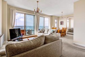a living room with a couch and a television and a table at Pass the Keys Stunning Sea Front Views in Westcliff-On-Sea