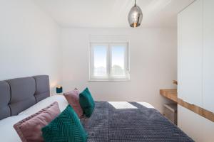 sypialnia z łóżkiem z poduszkami i oknem w obiekcie Skyline Luxe w mieście Zadar