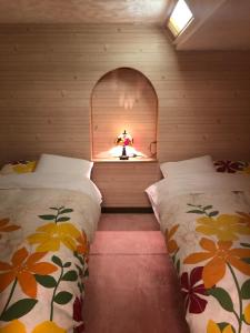 two beds in a small room with a window at Pension Locomotion in Niseko