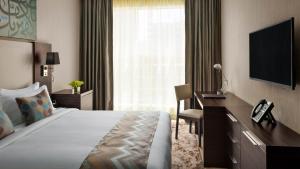 a hotel room with a bed and a desk and a television at M Hotel Makkah by Millennium in Makkah