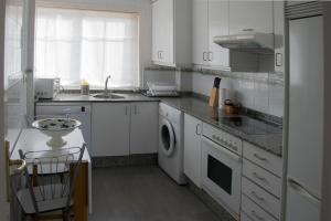 uma cozinha branca com um lavatório e uma máquina de lavar louça em Maravilloso apartamento con vistas al mar em Baiona