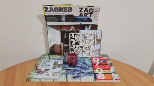 einen Glastisch mit einer Zeitschrift, einem Getränk und einer Zeitung in der Unterkunft Apartman "Britanac" in Zagreb