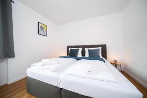 um quarto com uma cama grande com lençóis brancos e almofadas azuis em Favorite Stays - Suite And More - Neuss em Neuss