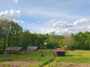 a group of buildings in a field with trees at Moulin Du Pommier Glamping & Camping in Saulgond