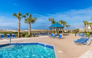 a pool with chairs and a gazebo and palm trees at Phoenix East 904 in Orange Beach