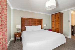 a bedroom with a white bed and a wooden headboard at Woodford Bridge Country Club in Milton Damerel +53 photos